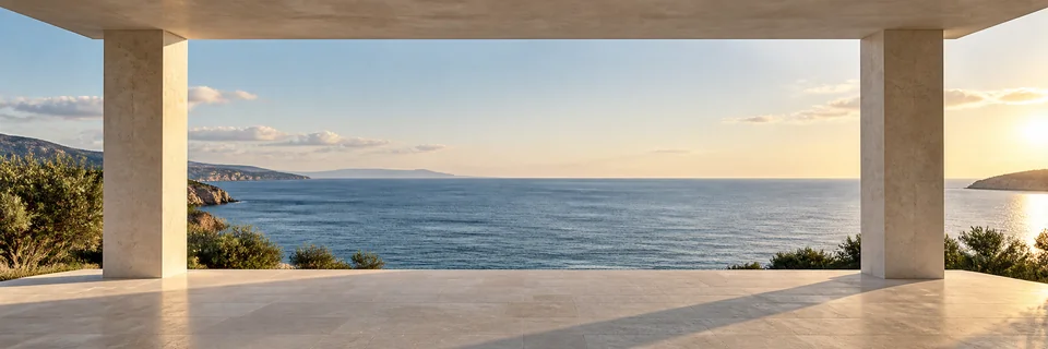 A contemporary limestone terrace with clean rectangular piers framing the sea in warm evening light